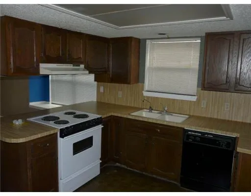 a kitchen with granite countertop stainless steel appliances a sink stove and cabinets
