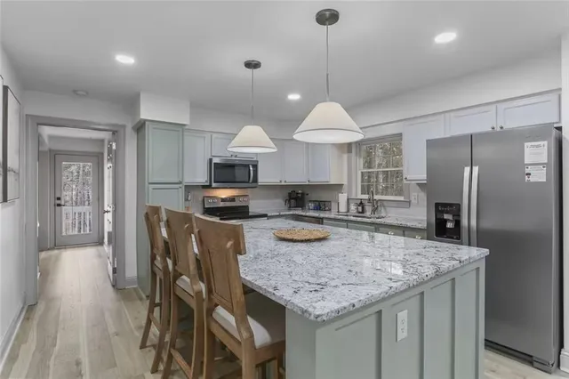 a kitchen with stainless steel appliances granite countertop a kitchen island a stove a table and chairs