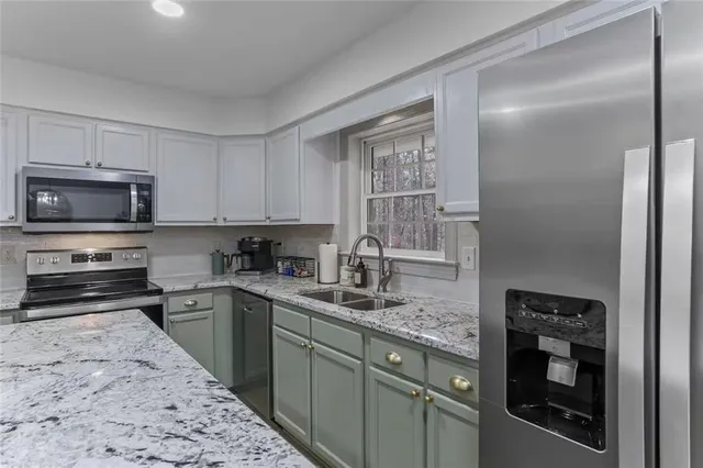 a kitchen with stainless steel appliances granite countertop a stove a sink and a microwave