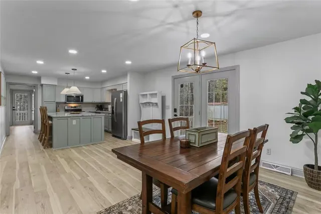a dining room with wooden floor a chandelier a wooden table and chairs