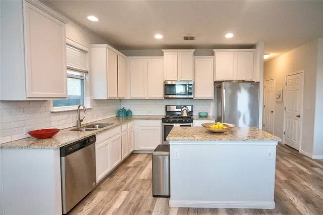 a kitchen with stainless steel appliances granite countertop a sink stove and refrigerator