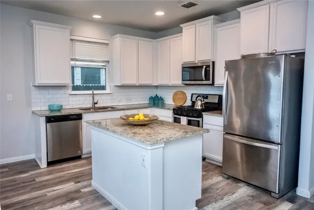 a kitchen with stainless steel appliances granite countertop a refrigerator stove microwave and sink