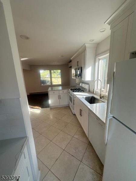 56 Buena Vista Road, Unit 1 Cedar Grove, NJ 07009 - Photo 4 of 16 a large white kitchen with a sink a microwave and cabinets