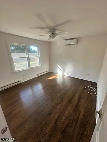 an empty room with wooden floor fan and windows