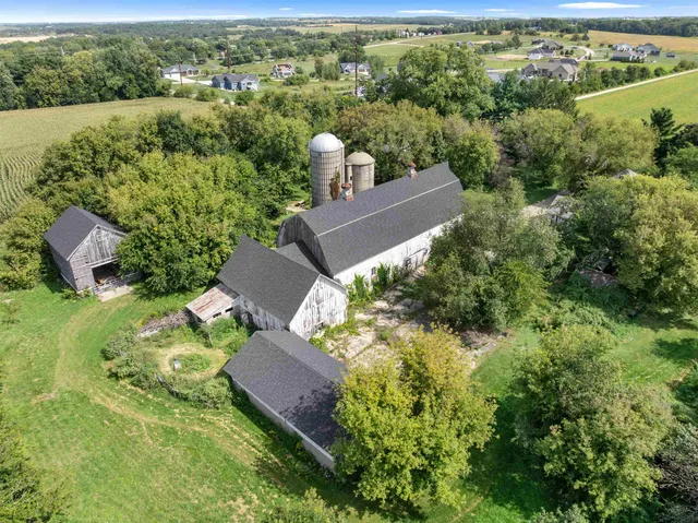 an aerial view of a house with a yard lake and trees all around