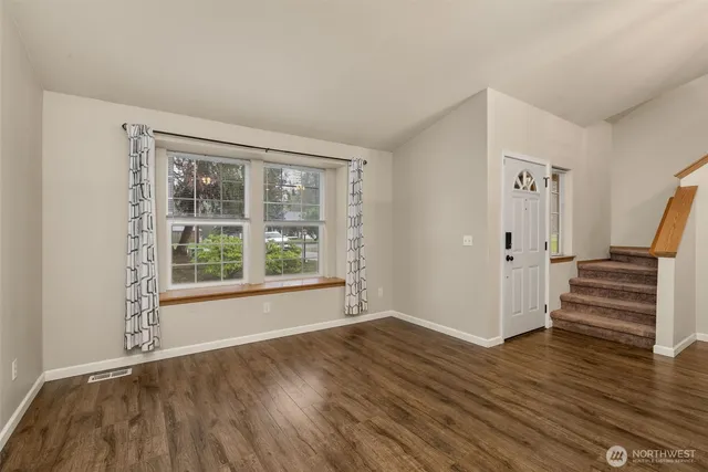 a view of an empty room with window fireplace and wooden floor