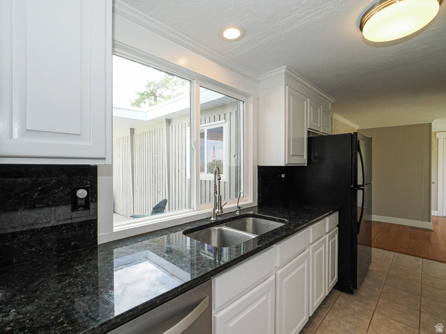 154 East 3000th Street South Bountiful, UT 84010 - Photo 5 of 37 Kitchen featuring a stainless steel double sink with a gooseneck faucet, dark countertops, white cabinetry with crown molding, and a black refrigerator
