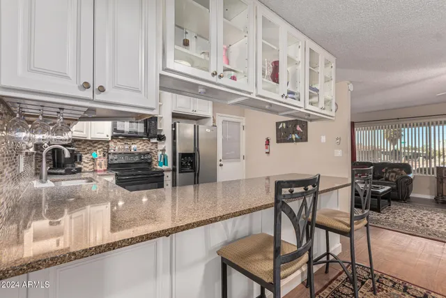 a kitchen with stainless steel appliances granite countertop a table and chairs in it