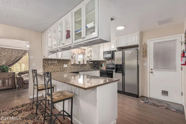 a kitchen with stainless steel appliances granite countertop a refrigerator a stove and a wooden floors