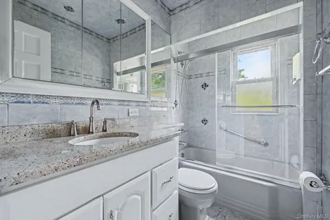 a bathroom with a granite countertop sink toilet and shower
