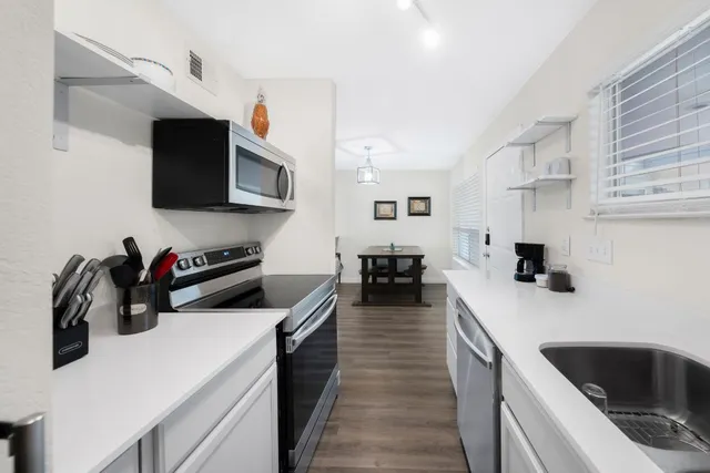 a kitchen with a sink dishwasher stove and microwave with wooden floor