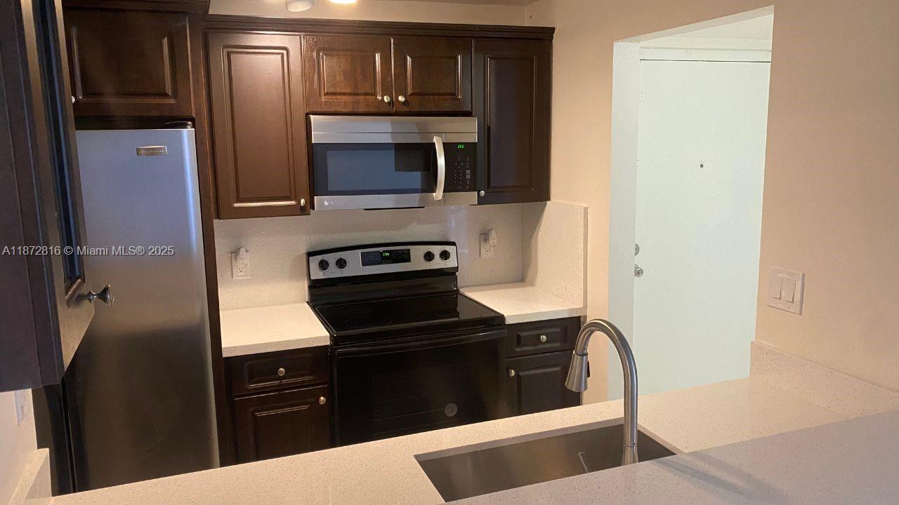 7075 Northwest 186th Street, Unit C110 Hialeah, FL 33015 - Photo 4 of 16 a kitchen with a refrigerator stove and microwave