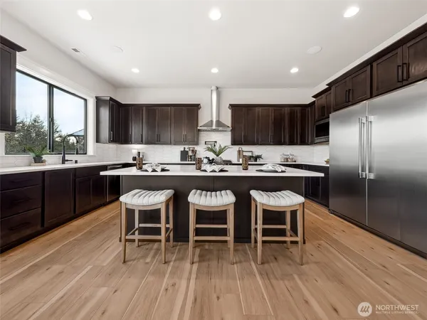 a kitchen with stainless steel appliances kitchen island granite countertop a table chairs a sink and a refrigerator