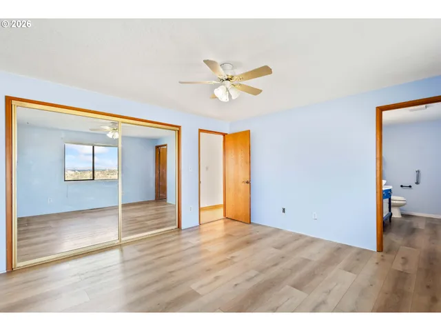 a view of an empty room with window and wooden floor