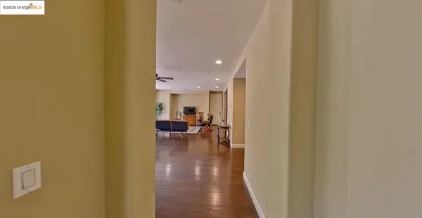 an empty room with chandelier fan and windows