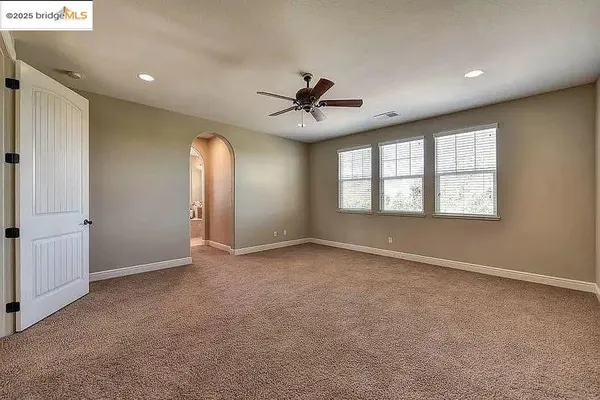 a view of an empty room and kitchen with sink wooden floor and windows