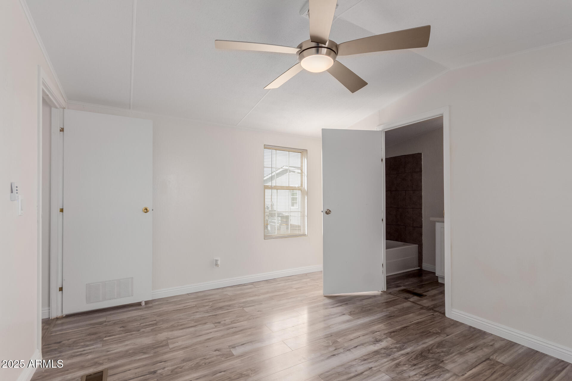2000 South Apache Road, Unit 276 Buckeye, AZ 85326 - Photo 11 of 27 an empty room with wooden floor chandelier fan and windows