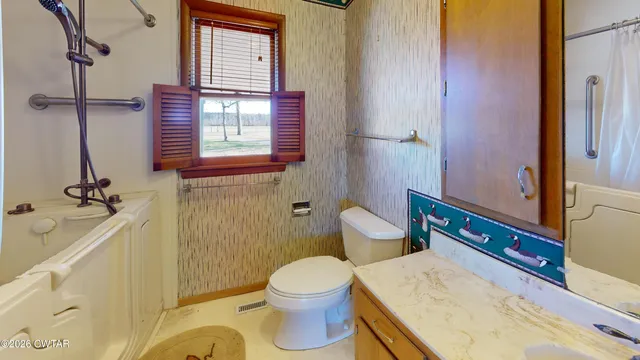 a bathroom with a granite countertop toilet a sink and a mirror
