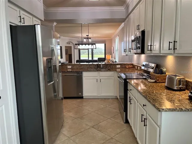 a kitchen with stainless steel appliances granite countertop a sink a stove a refrigerator and island