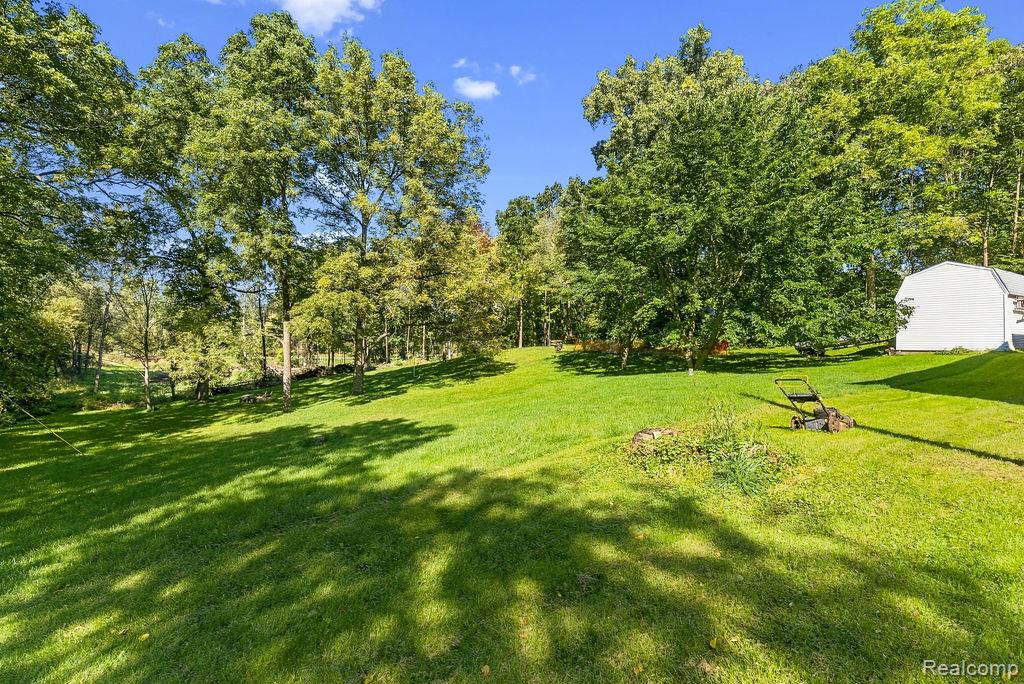 87 Burley Road Columbiaville, MI 48421 - Photo 29 of 31 Expansive green lawn with mature trees and a white outbuilding