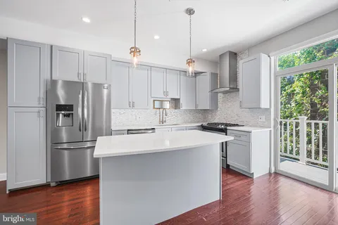 a kitchen with stainless steel appliances granite countertop a refrigerator a sink dishwasher a stove and white countertops with wooden floor