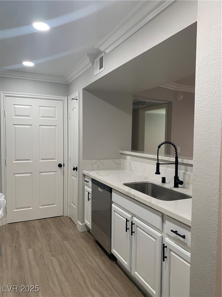 8101 West Flamingo Road, Unit 1102 Las Vegas, NV 89147 - Photo 29 of 54 Kitchen featuring dishwashing machine, ornamental molding, wood finished floors, white cabinetry, and light stone countertops
