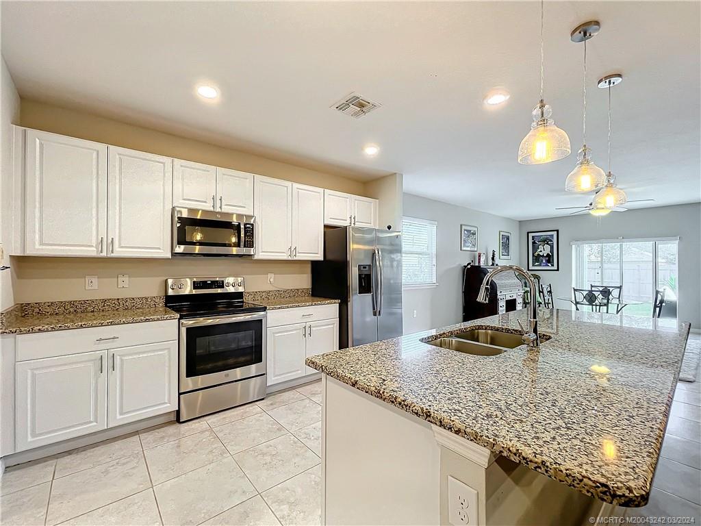 a kitchen with kitchen island granite countertop a stove sink and microwave