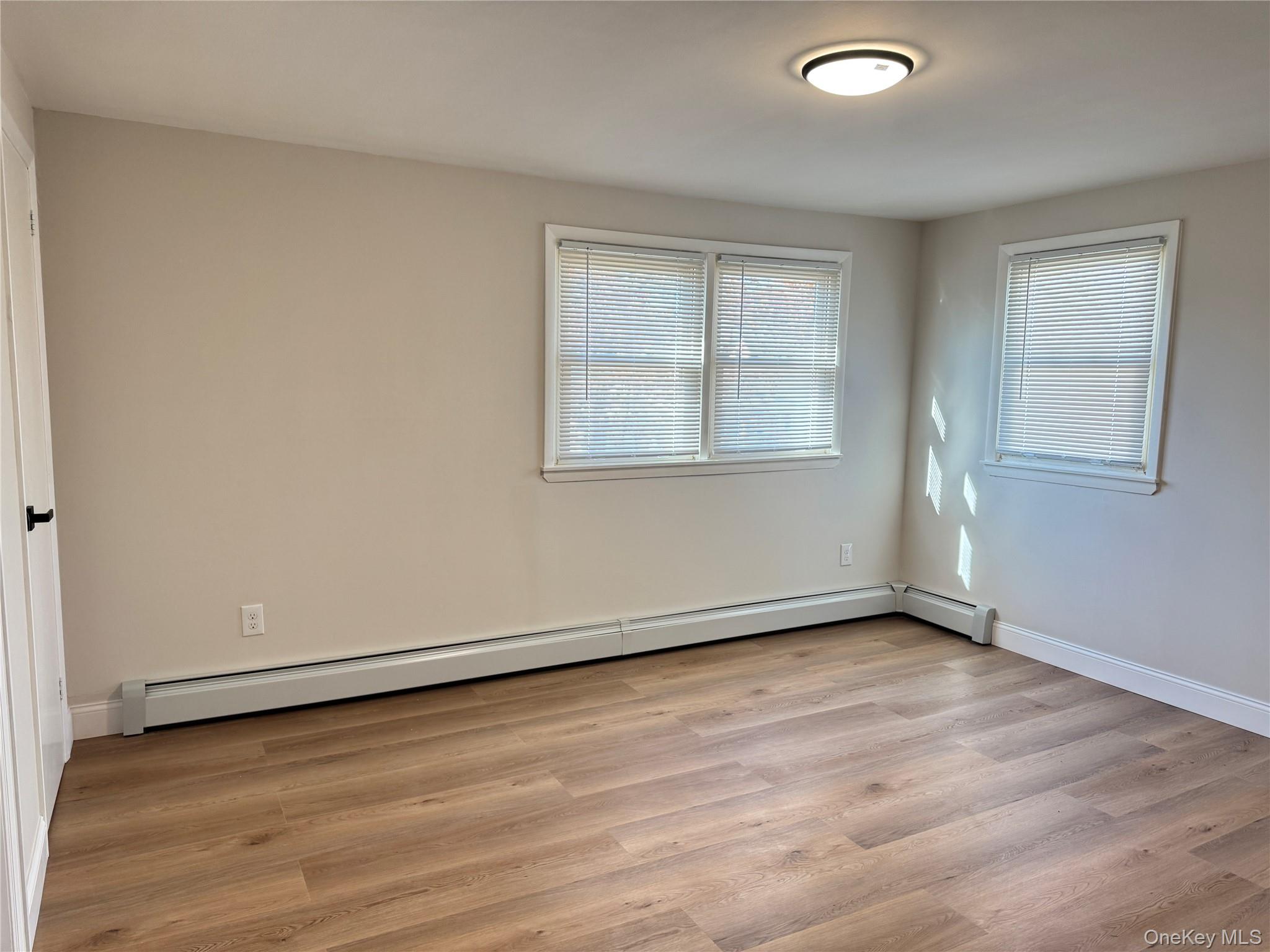 129 Spring Lane Levittown, NY 11756 - Photo 6 of 18 an empty room with wooden floor and windows