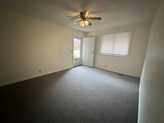 an empty room with a window and a ceiling fan