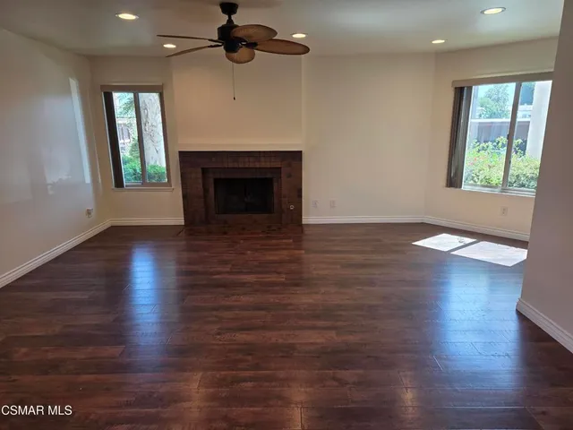 an empty room with wooden floor fireplace and windows