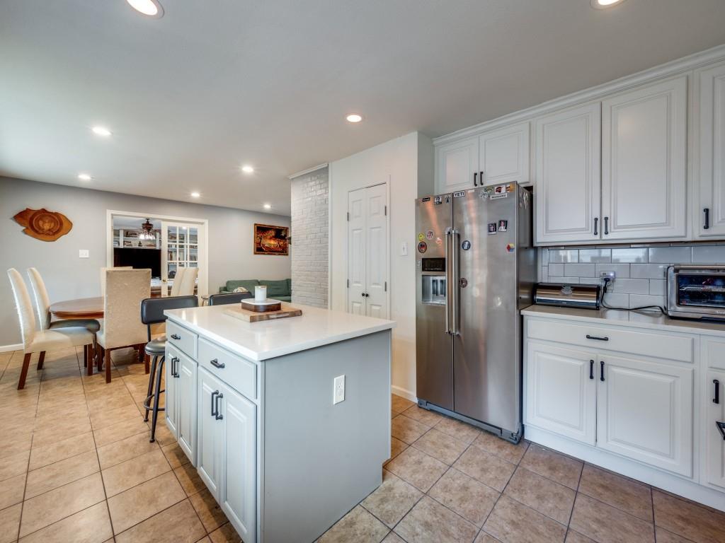 9835 Estate Lane Dallas, TX 75238 - Photo 12 of 25 Kitchen featuring a kitchen island, high quality fridge, light tile patterned floors, a kitchen breakfast bar, and decorative backsplash