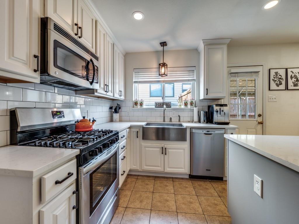 9835 Estate Lane Dallas, TX 75238 - Photo 14 of 25 Kitchen featuring stainless steel appliances, hanging light fixtures, light tile patterned flooring, light stone counters, and white cabinets