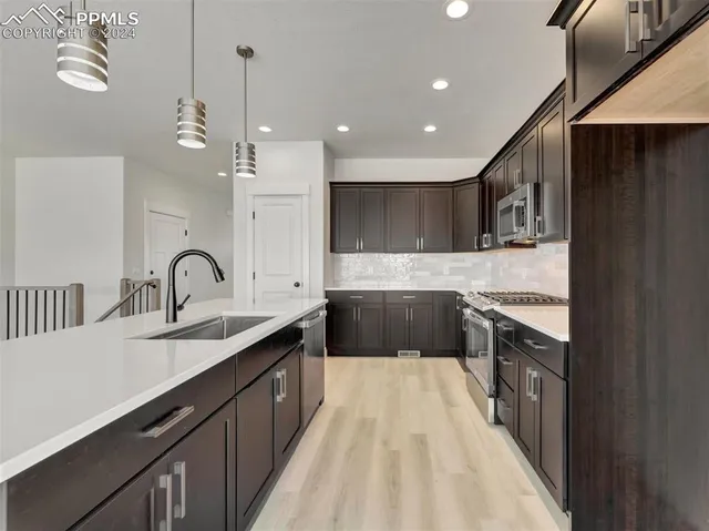 a kitchen with kitchen island granite countertop a sink stainless steel appliances and cabinets
