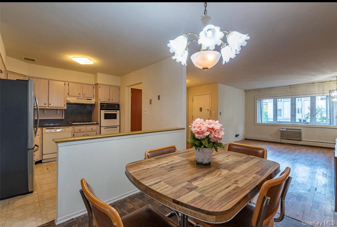 18-16 Bell Boulevard, Unit 2 Queens, NY 11360 - Photo 2 of 8 a dining room with wooden floor a chandelier a wooden table and chairs