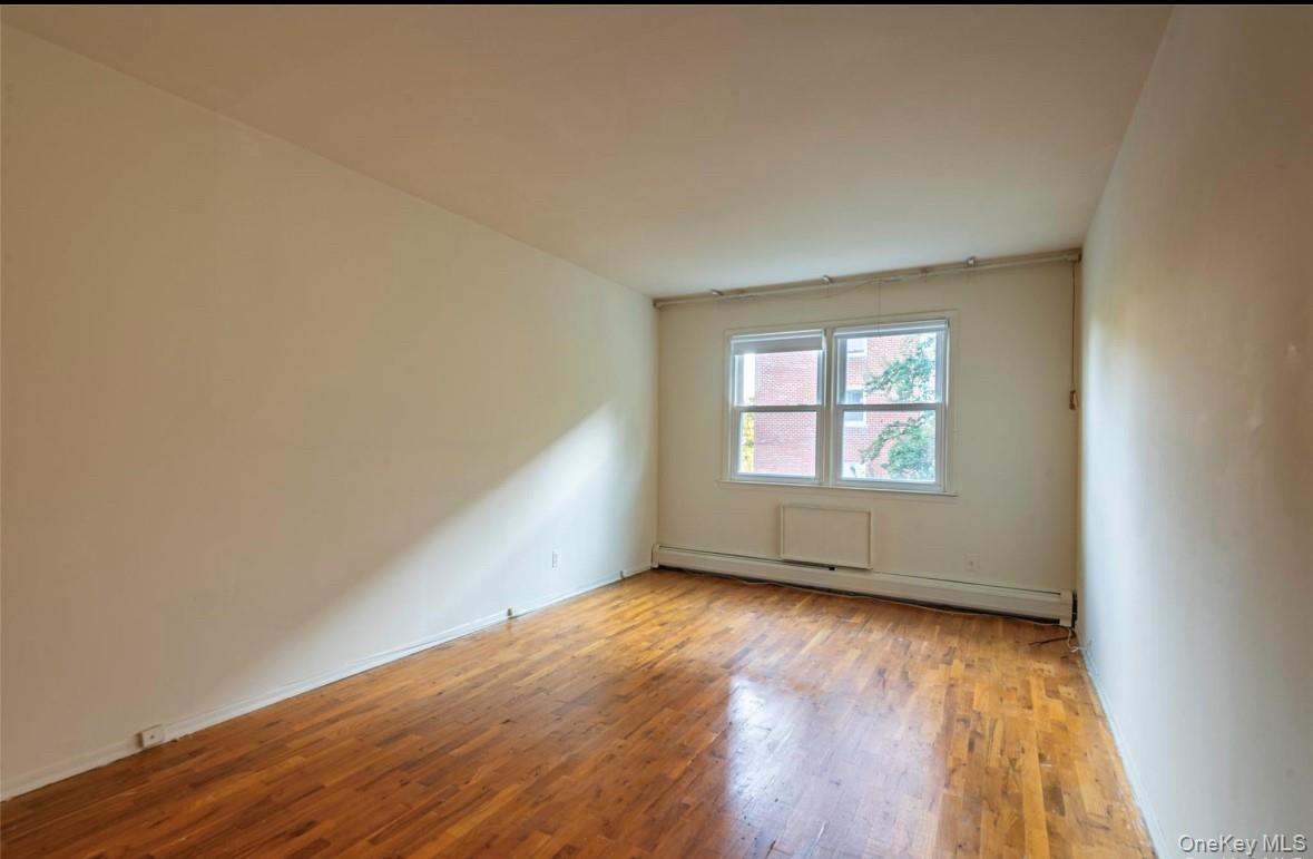 18-16 Bell Boulevard, Unit 2 Queens, NY 11360 - Photo 5 of 8 an empty room with wooden floor and windows