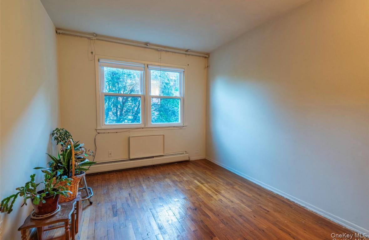 18-16 Bell Boulevard, Unit 2 Queens, NY 11360 - Photo 7 of 8 an empty room with wooden floor and a window