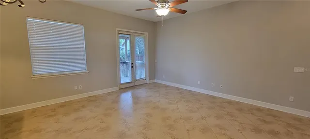 an empty room with windows and chandelier fan