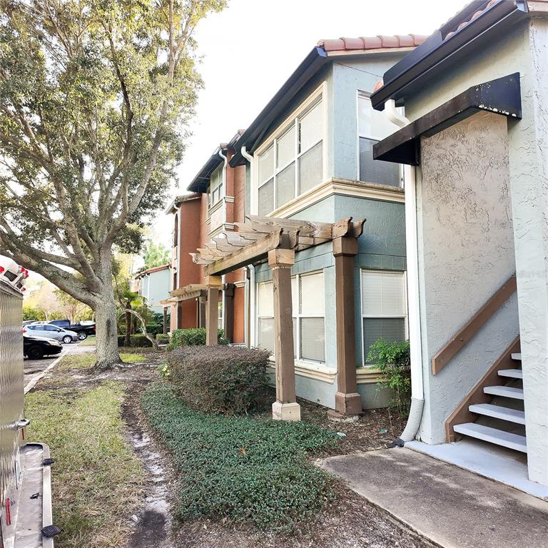 a view of a white house next to a yard with large trees