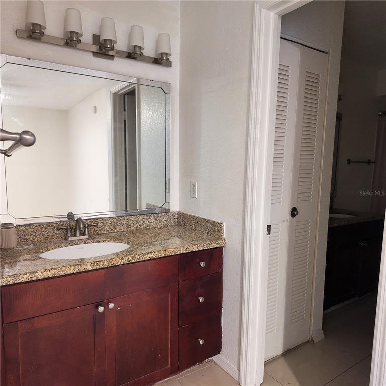 5152 Conroy Road, Unit 1317 Orlando, FL 32811 - Photo 14 of 21 a bathroom with a granite countertop sink and a mirror