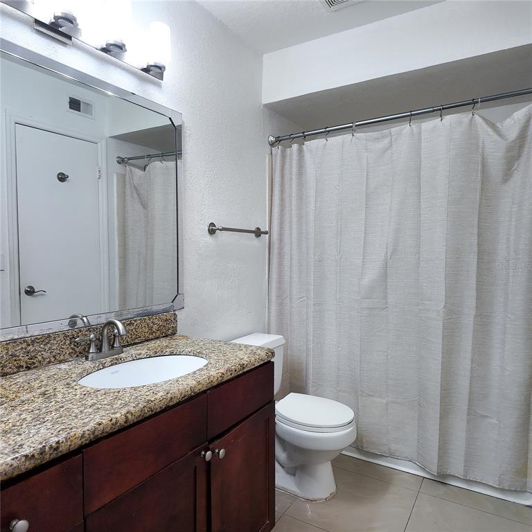 5152 Conroy Road, Unit 1317 Orlando, FL 32811 - Photo 16 of 21 a bathroom with a granite countertop sink toilet and a mirror