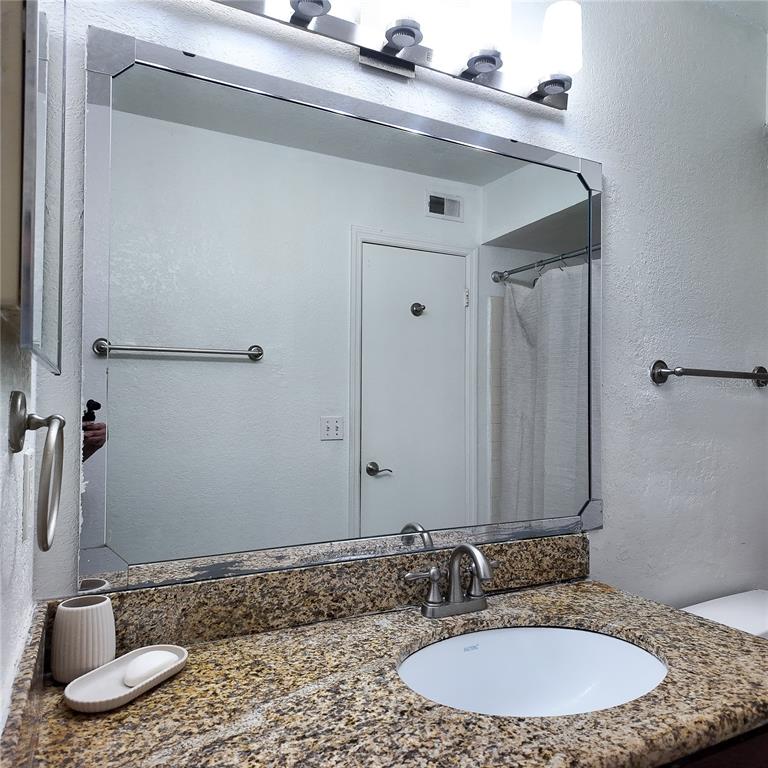 5152 Conroy Road, Unit 1317 Orlando, FL 32811 - Photo 17 of 21 a bathroom with a granite countertop sink and a mirror
