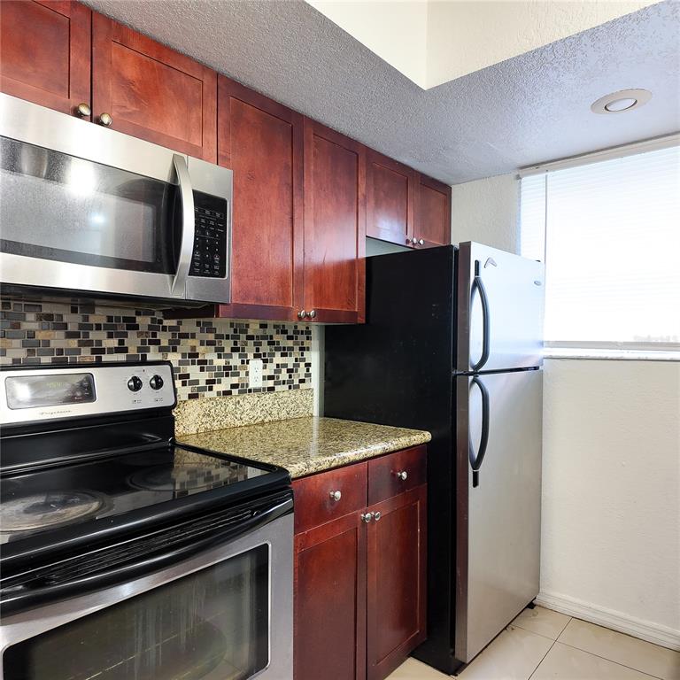 5152 Conroy Road, Unit 1317 Orlando, FL 32811 - Photo 6 of 21 a kitchen with granite countertop stainless steel appliances and refrigerator