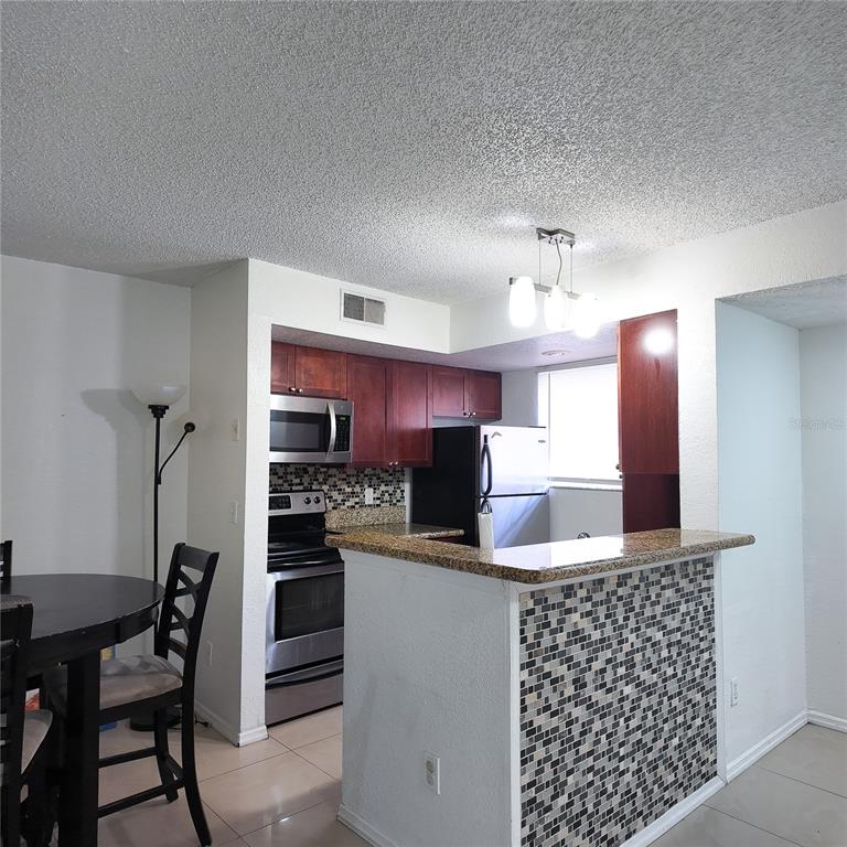 5152 Conroy Road, Unit 1317 Orlando, FL 32811 - Photo 8 of 21 a kitchen with stainless steel appliances kitchen island granite countertop a refrigerator and a stove top oven