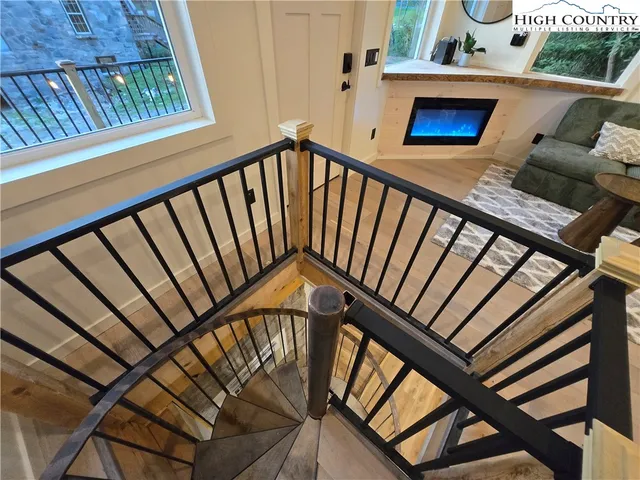 a view of an empty room with wooden floor and a fireplace