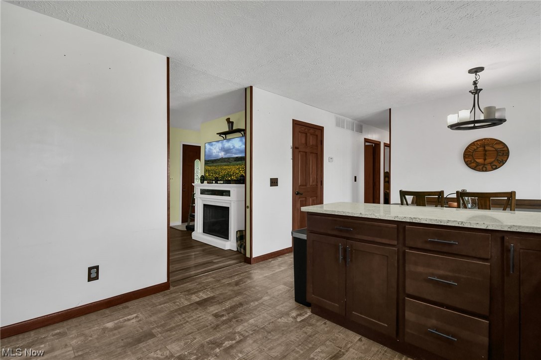 681 Rocky Point Road Fleming, OH 45729 - Photo 10 of 33 Kitchen with dark hardwood flooring, a textured ceiling, dark brown cabinets, and pendant lighting