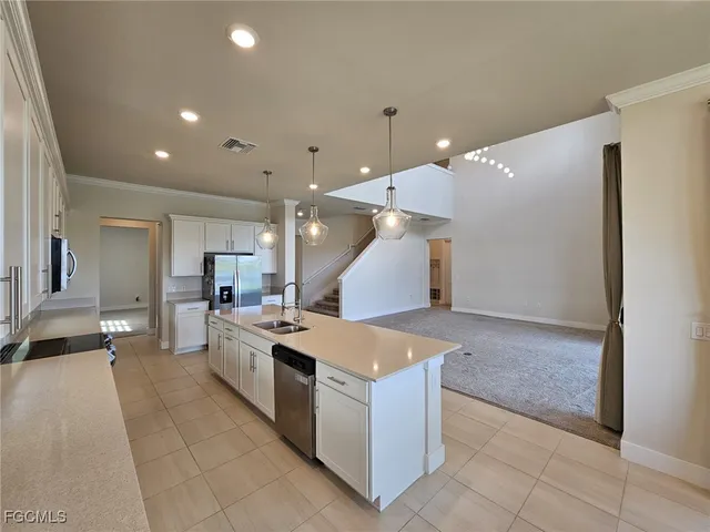 a large kitchen with stainless steel appliances a large counter top a stove and a refrigerator