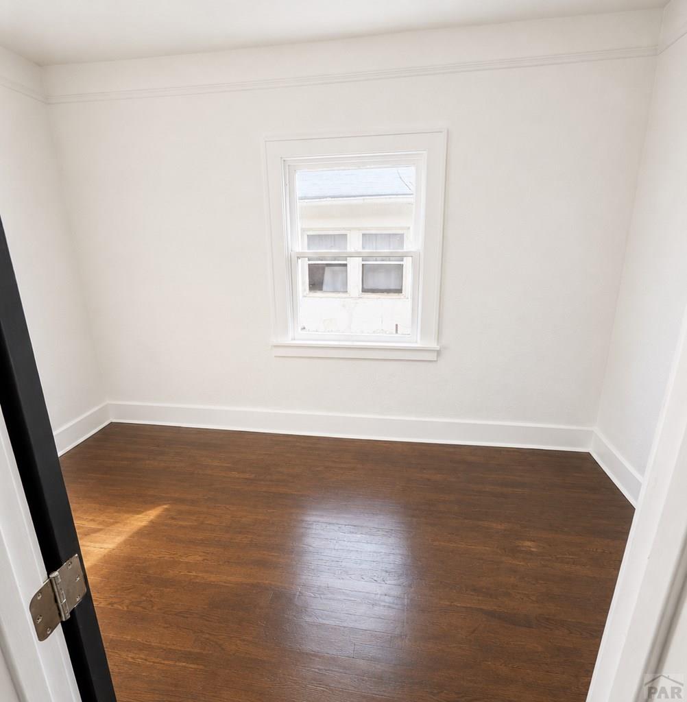 207 Spring Street Pueblo, CO 81003 - Photo 2 of 11 an empty room with wooden floor and windows