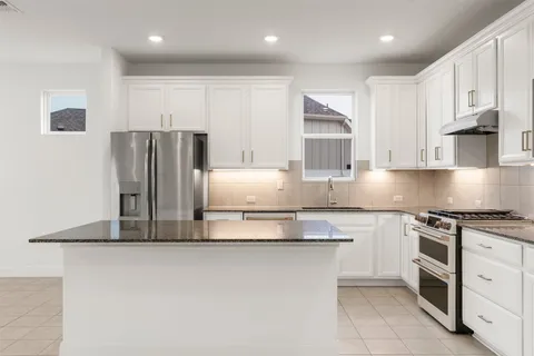 a kitchen with granite countertop white cabinets and stainless steel appliances