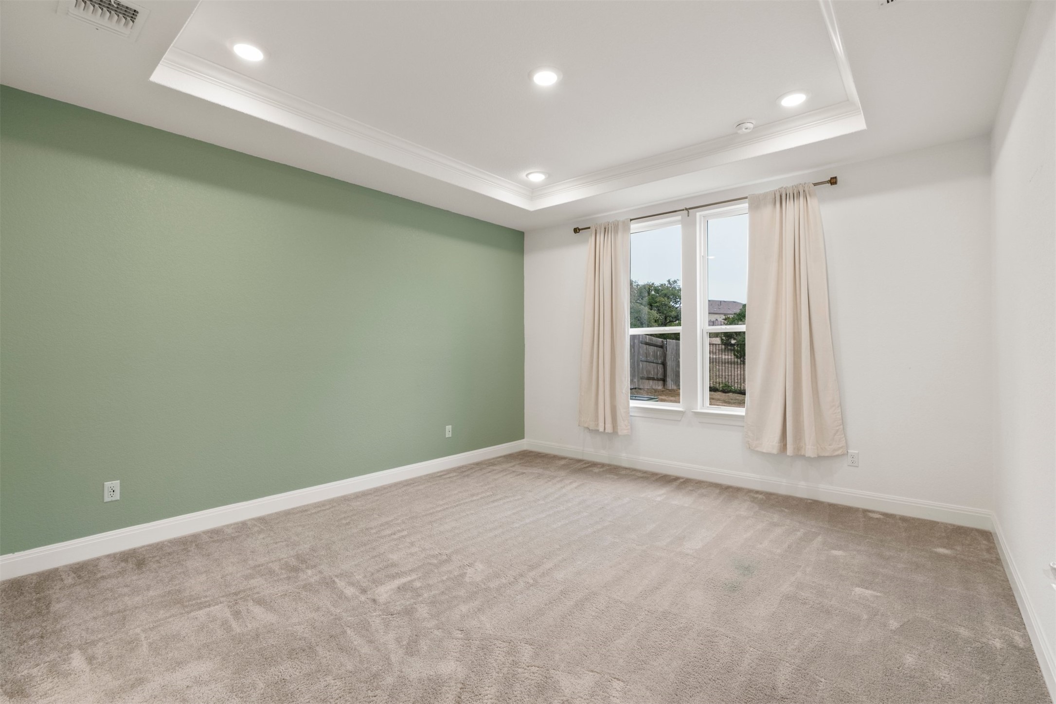 302 Barn Hill Loop Dripping Springs, TX 78620 - Photo 18 of 40 A tray ceiling and large dual-pane windows bring in natural light while keeping the room calm and comfortable throughout the day