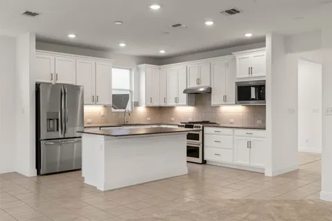 an empty room with windows and ceiling fan